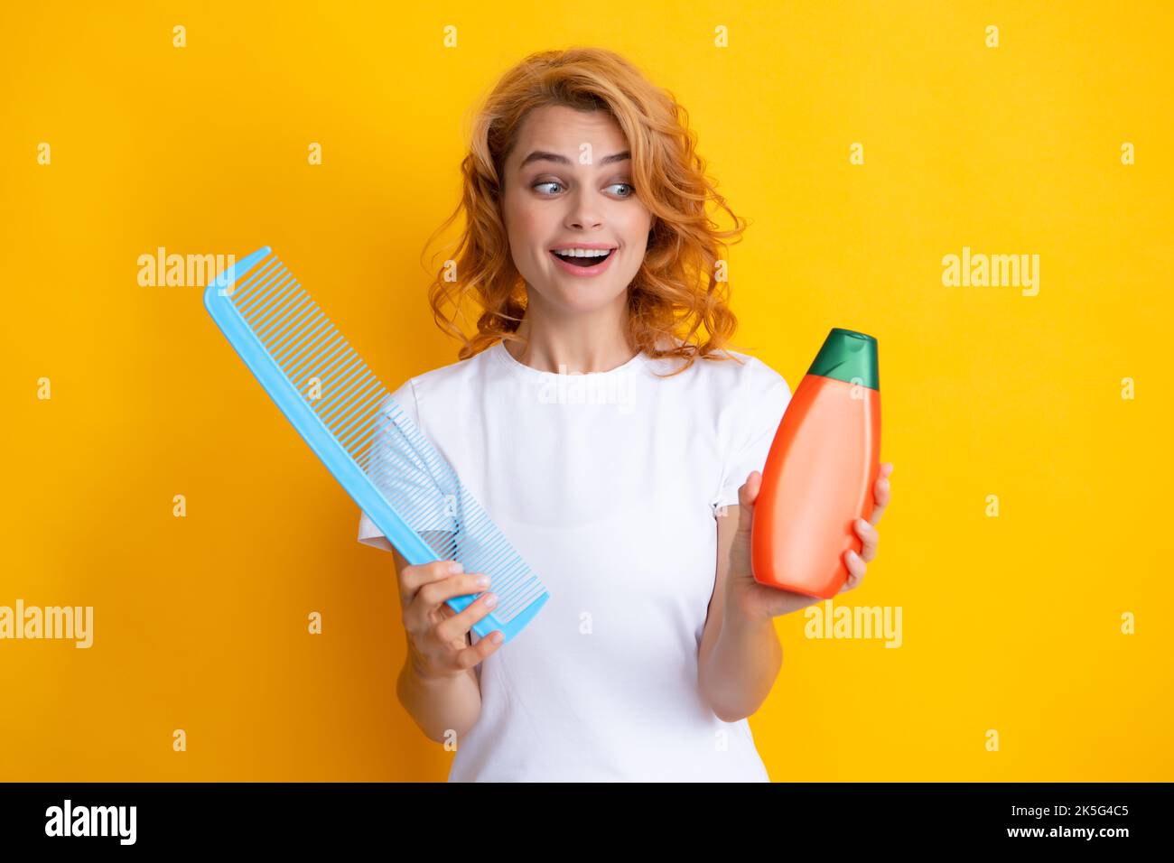 Women hair care. Girl combing hair. Redhead woman with a comb, isolated