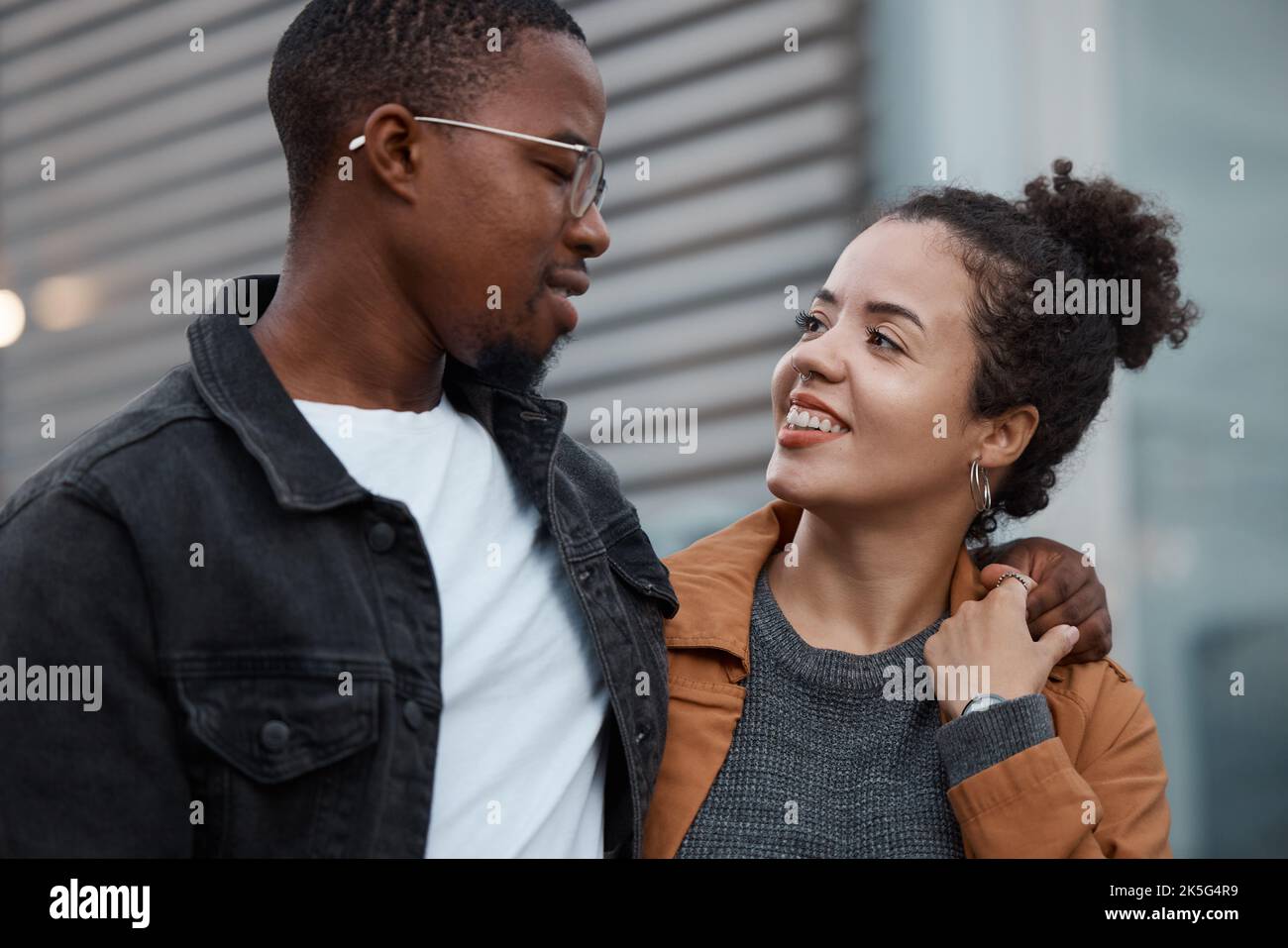Couple, love and diversity with a man and woman outdoor walking together in an urban city during the day. Dating, relationship and romance with a Stock Photo