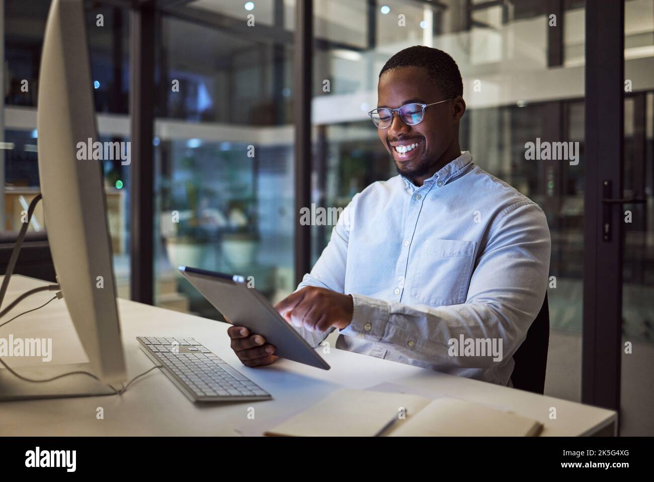 Businessman working on digital tablet late in office at night, happy ...