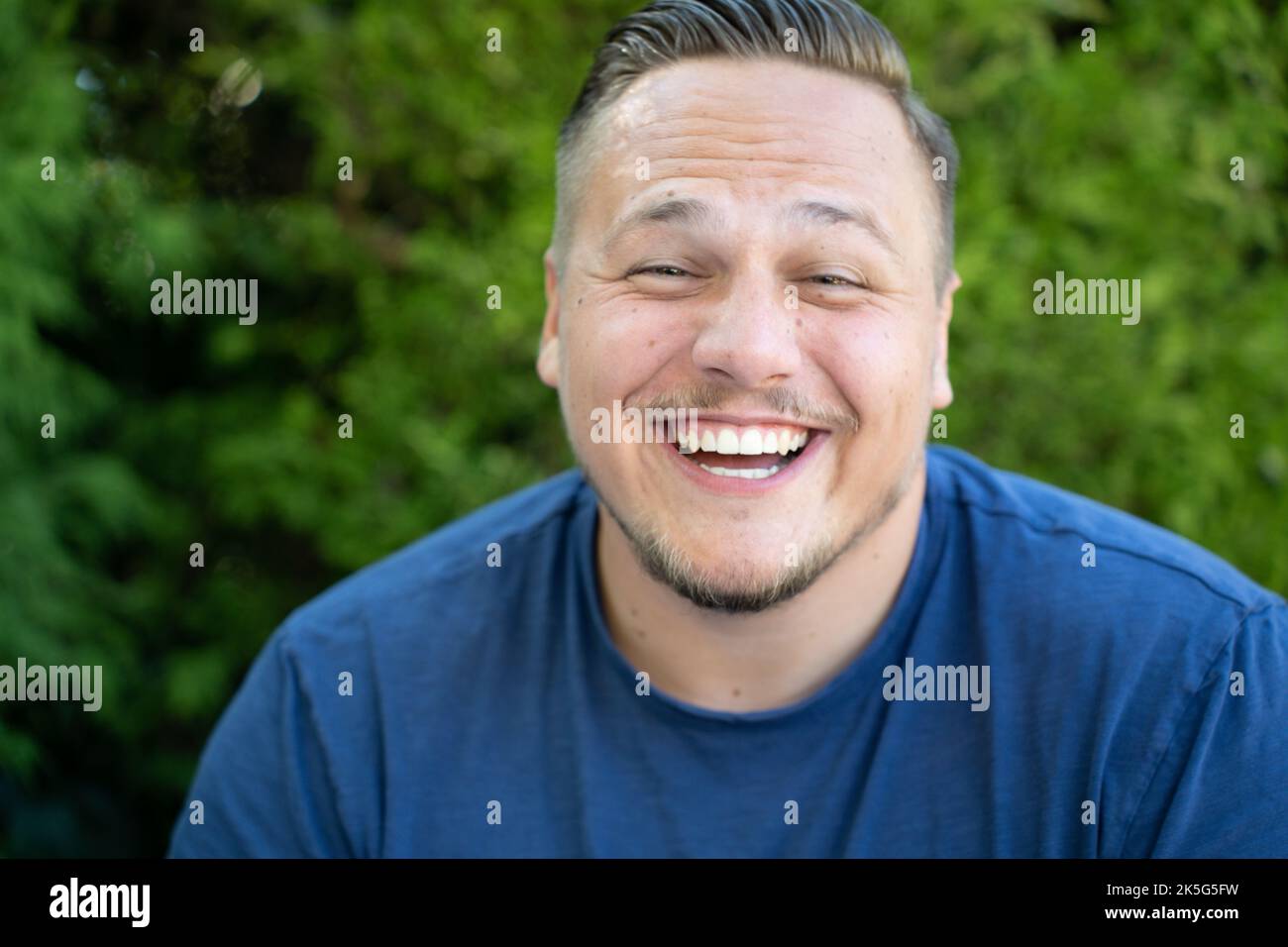 Young man enjoying a good joke laughing happily with a beaming smile in close up Stock Photo