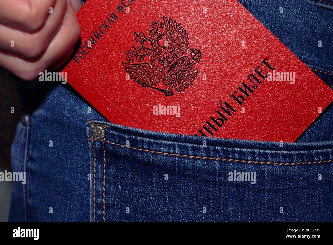 A close up of a hand taking a Russian military ID out of pants pocket