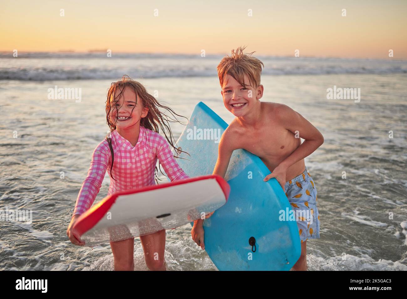 Happy children, beach and learning to surf for fun and bonding on bali summer vacation. Kids, boy and girl siblings on tropical holiday while surfing Stock Photo
