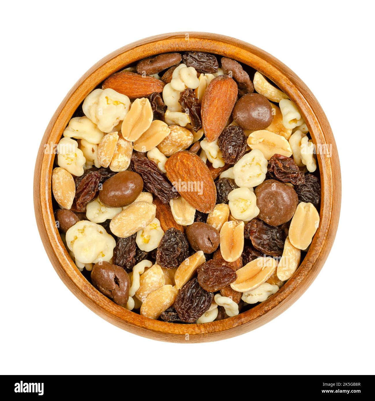 Nut chocolate mix, in wooden bowl. Sweet snack food and mixture of raisins, roasted peanuts and almonds, with milk and white chocolate. Stock Photo