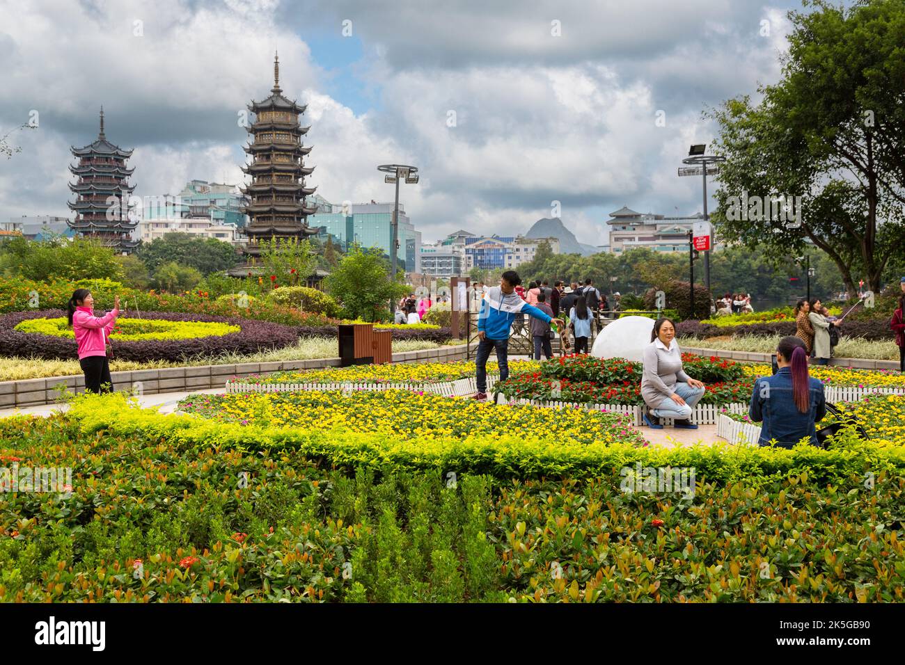 Guilin, China.  Visitors Taking Pictures in Gardens along Shan (Fir) Lake.  Sun and Moon Pagodas in Background. Stock Photo