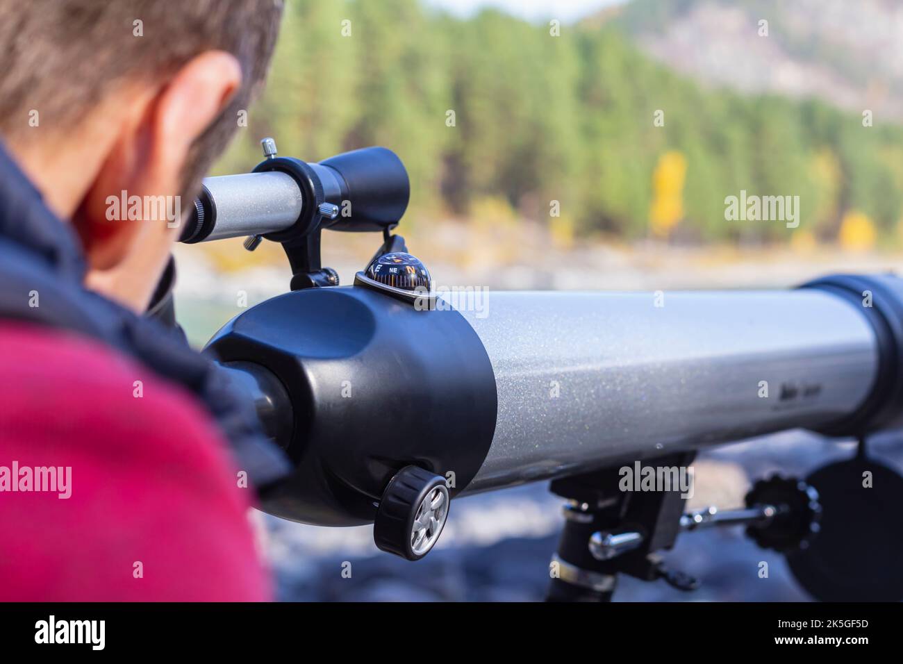 Attractive man looking into acular telescope, watch celestial body, focus on compass.Optical telescope, device instrument for land lunar or planetary Stock Photo