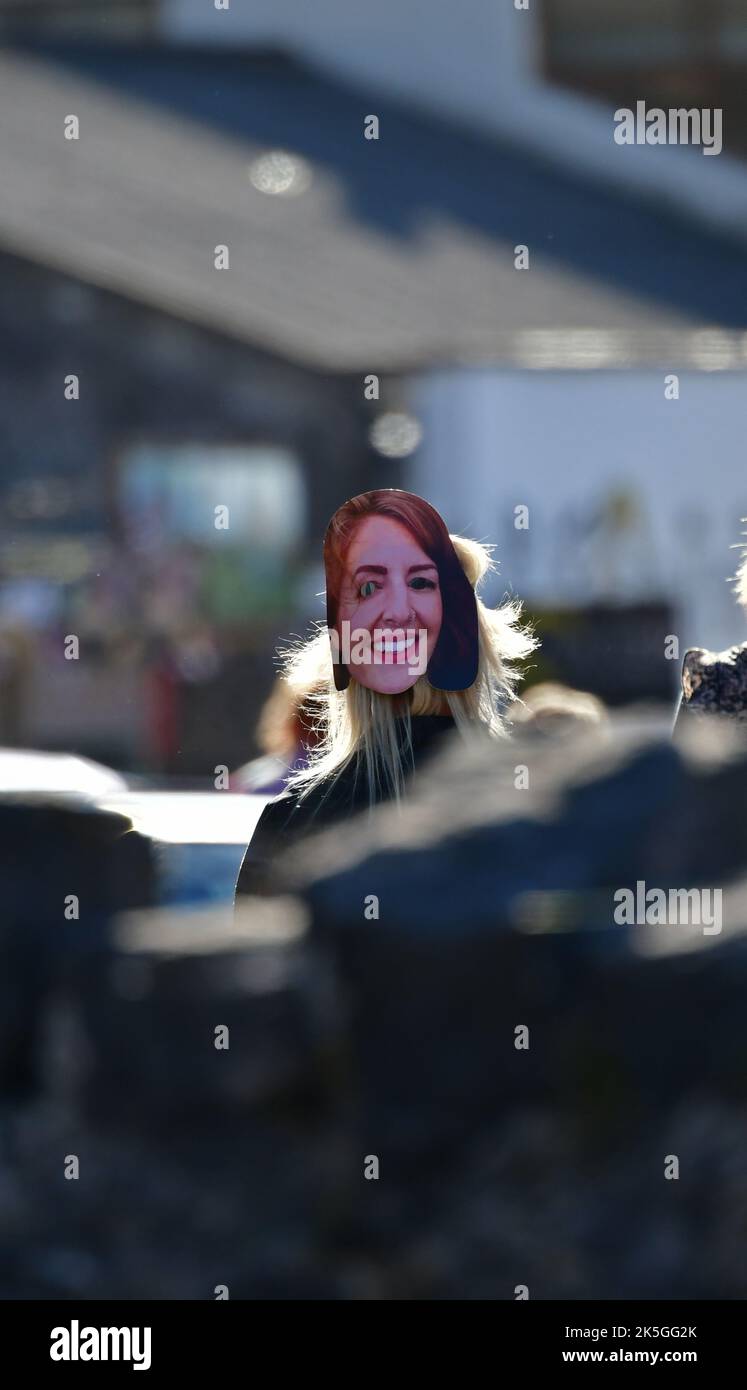 Cheddar, UK. 08th Oct, 2022. A person with friends are seen in Cheddar Gorge near shops wearing a LIZ TRUSS look alike mask on the back of her HEAD. Picture Credit: Robert Timoney/Alamy Live News Stock Photo