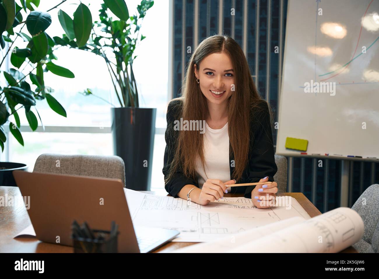 Smiling happy female architect posing for camera at work Stock Photo
