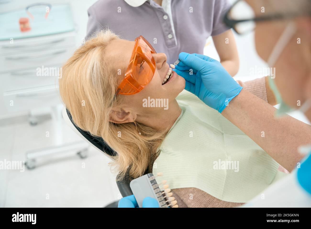 Dentist is comparing patient teeth with crown sampler in medicine center Stock Photo