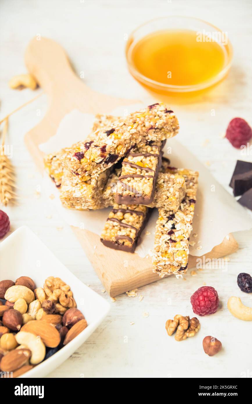 Various homemade granola bars with nuts, seeds, dark chocolate, honey and berries over a wooden board. Stock Photo