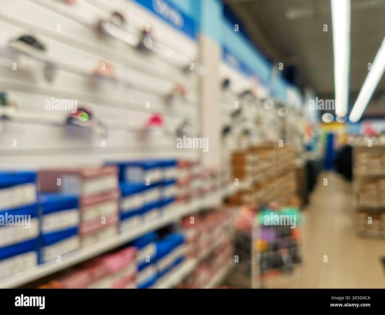 Abstract blur empty supermarket discount store aisle and product shelves interior defocused background. Rows of shelves with toys in a hypermall. Blur Stock Photo