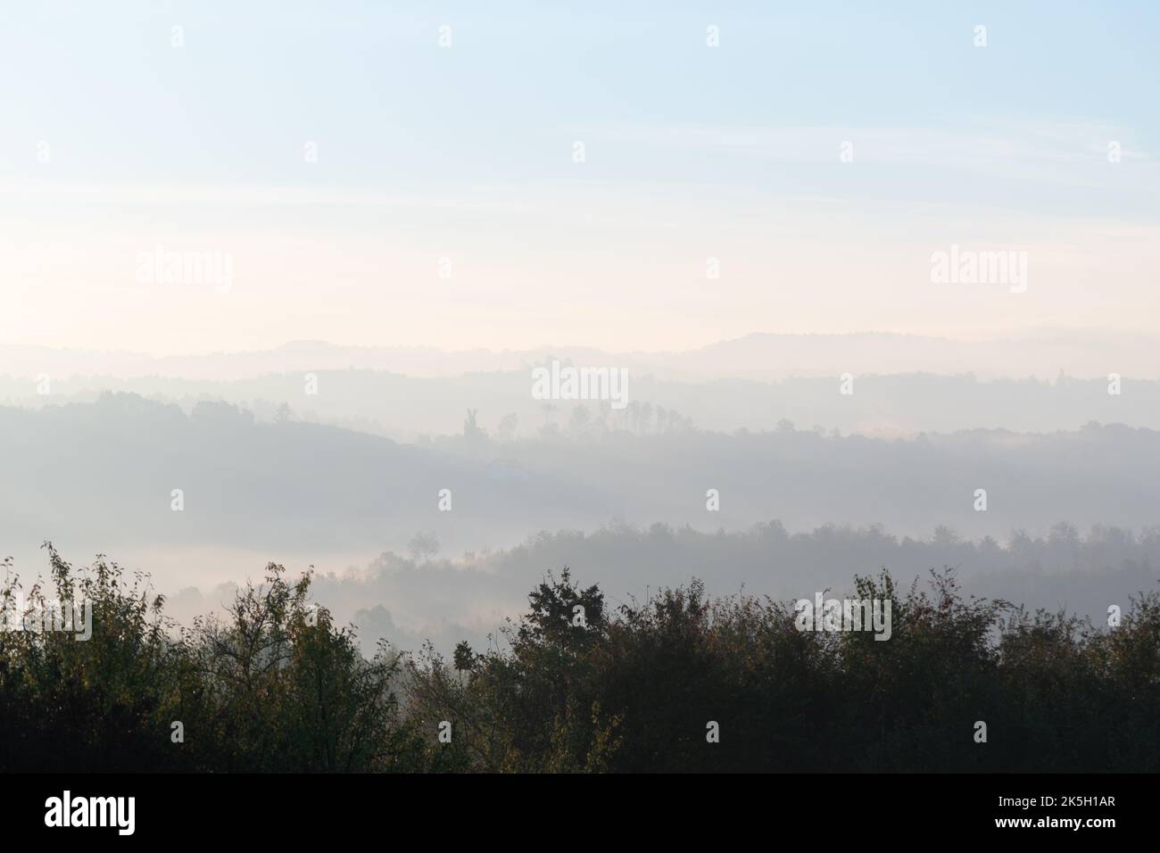 Hills with forest in fog at autumn morning, misty forest layers in autumn Stock Photo