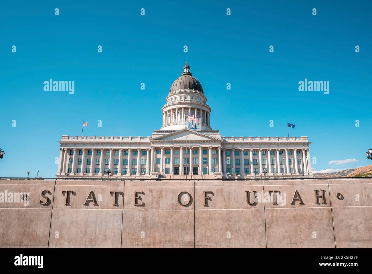 Flags waving at State Capitol building with clear blue sky in ...