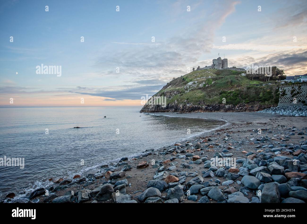 Criccieth Castle at sunset with moon in the sky seen from Criccieth beack, Gwnydd, Wales on 2 October 2022 Stock Photo