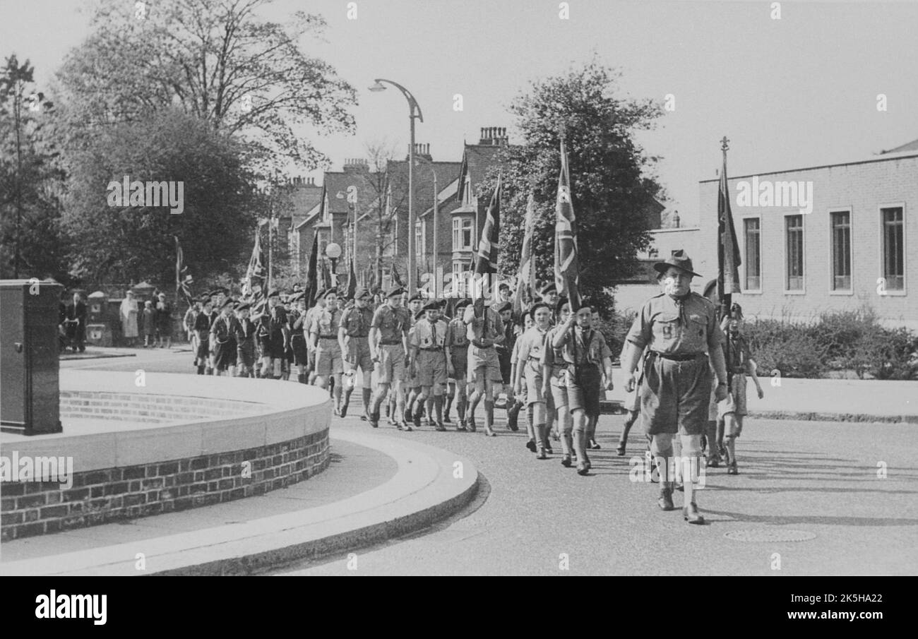 1950s. A parade led by Beckenham Boy Scouts marching around the roundabout at the junction of Rectory Road and Beckenham Road, Beckenham, Kent. On the right is the Beckenham Post Office building. Stock Photo