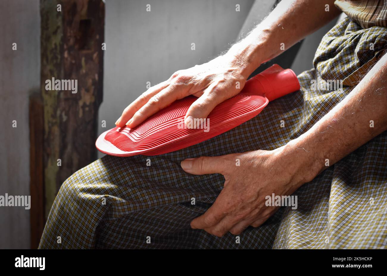 Thigh pain in Asian senior male patient. Concept of muscle sprain, sciatica or sciatic nerve pain. Therapy by rubber hot water bag. Stock Photo