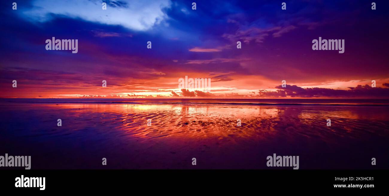 Panorama scene of sunset at Chaung Tha beach. Cloudy sky. Ending hour at seaside. Stock Photo