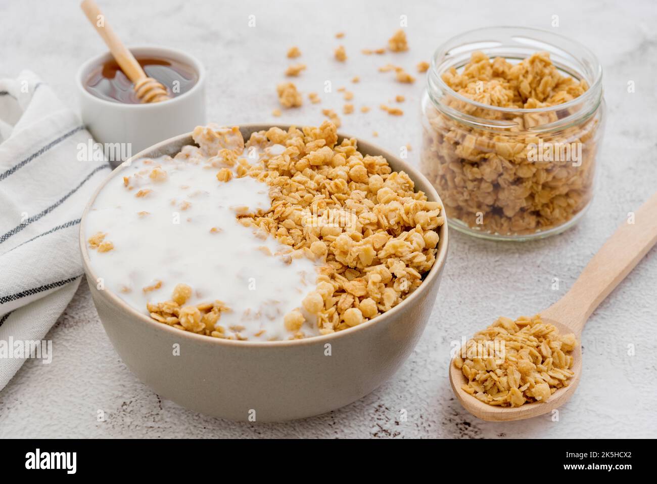 Dry breakfast cereals. Crunchy honey granola bowl and a glass of milk on a table. Healthy and fiber food. Breakfast time Stock Photo