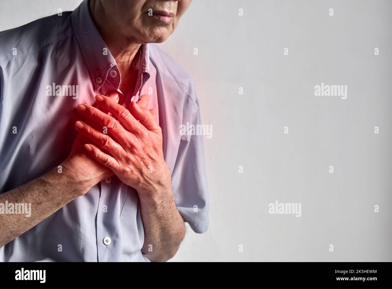 Asian elder man suffering from central chest pain. Chest pain can be caused by heart attack, myocardial infarct or ischemia, myocarditis, pneumonia, o Stock Photo