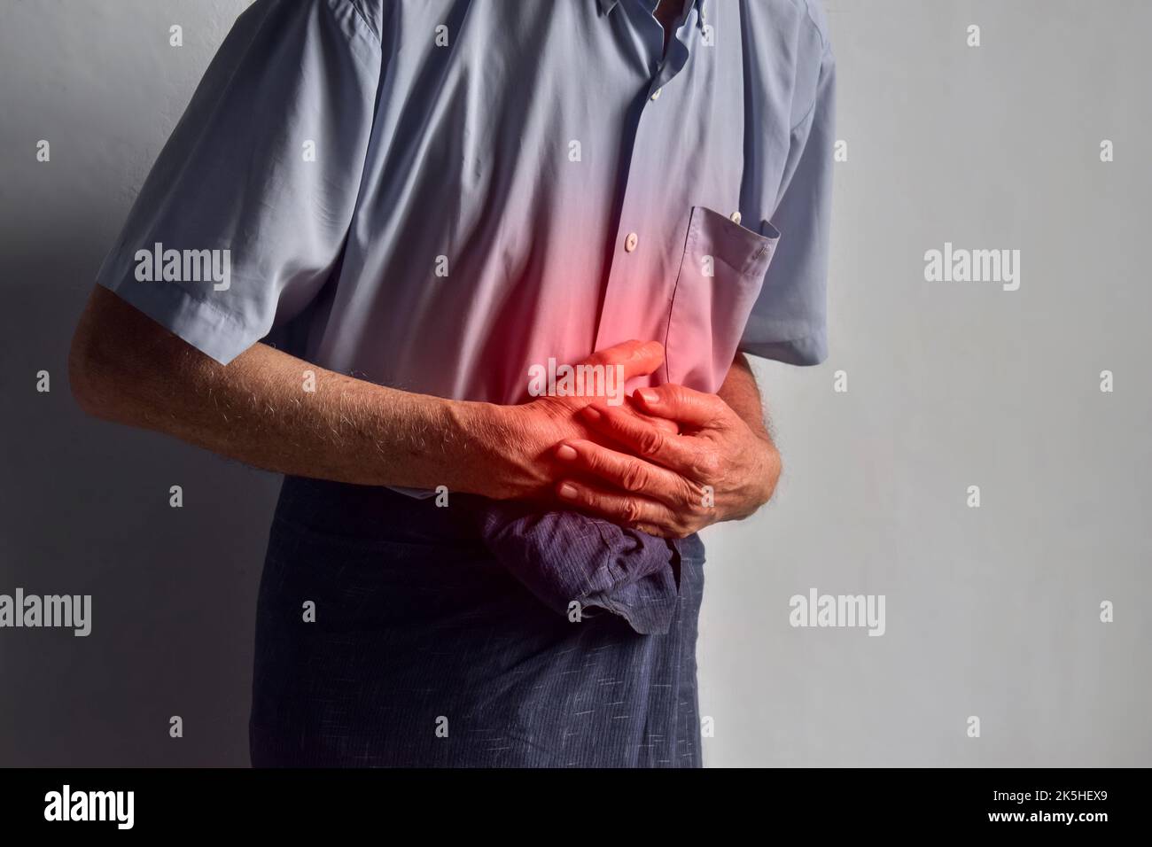 Asian elder man suffering from upper abdominal pain. It can be caused by stomach ache, enteritis, colitis, appendicitis, hepatitis, pancreatitis, food Stock Photo