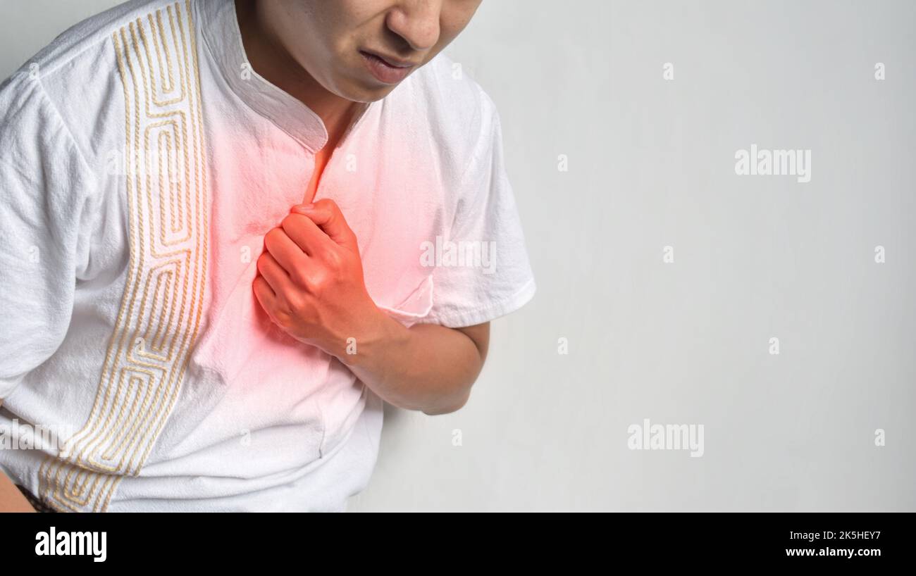 Asian young man suffering from central chest pain. Chest pain can be