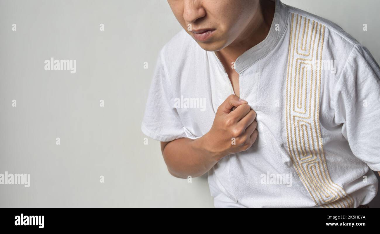 Asian young man suffering from central chest pain. Chest pain can be