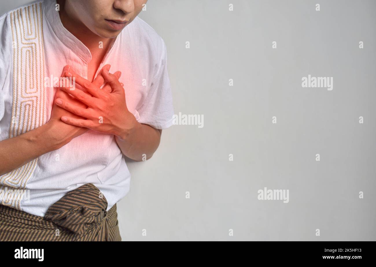 Asian young man suffering from central chest pain. Chest pain can be