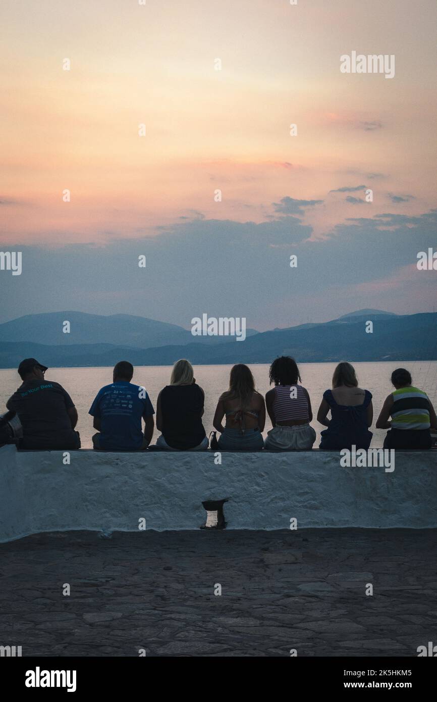 A group of people sitting and staring at the sunset Stock Photo - Alamy