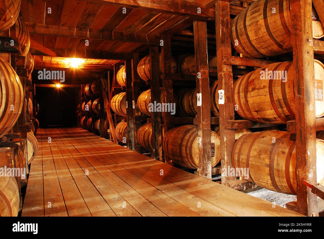 Kentucky Bourbon ages in charred white oak barrels inside a wooden storage facility at a distillery in Kentucky Stock Photo