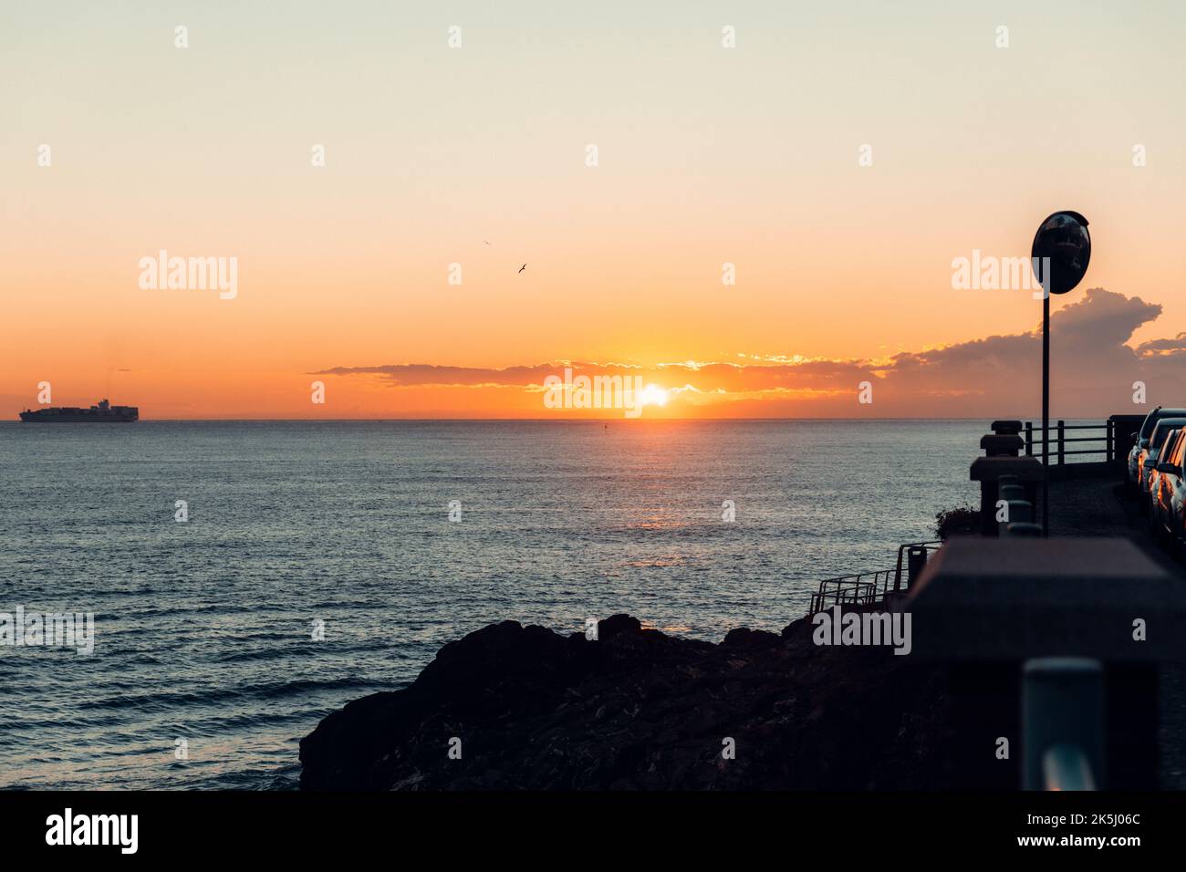 A ship on the horizon of sea at scenic sunset Stock Photo - Alamy