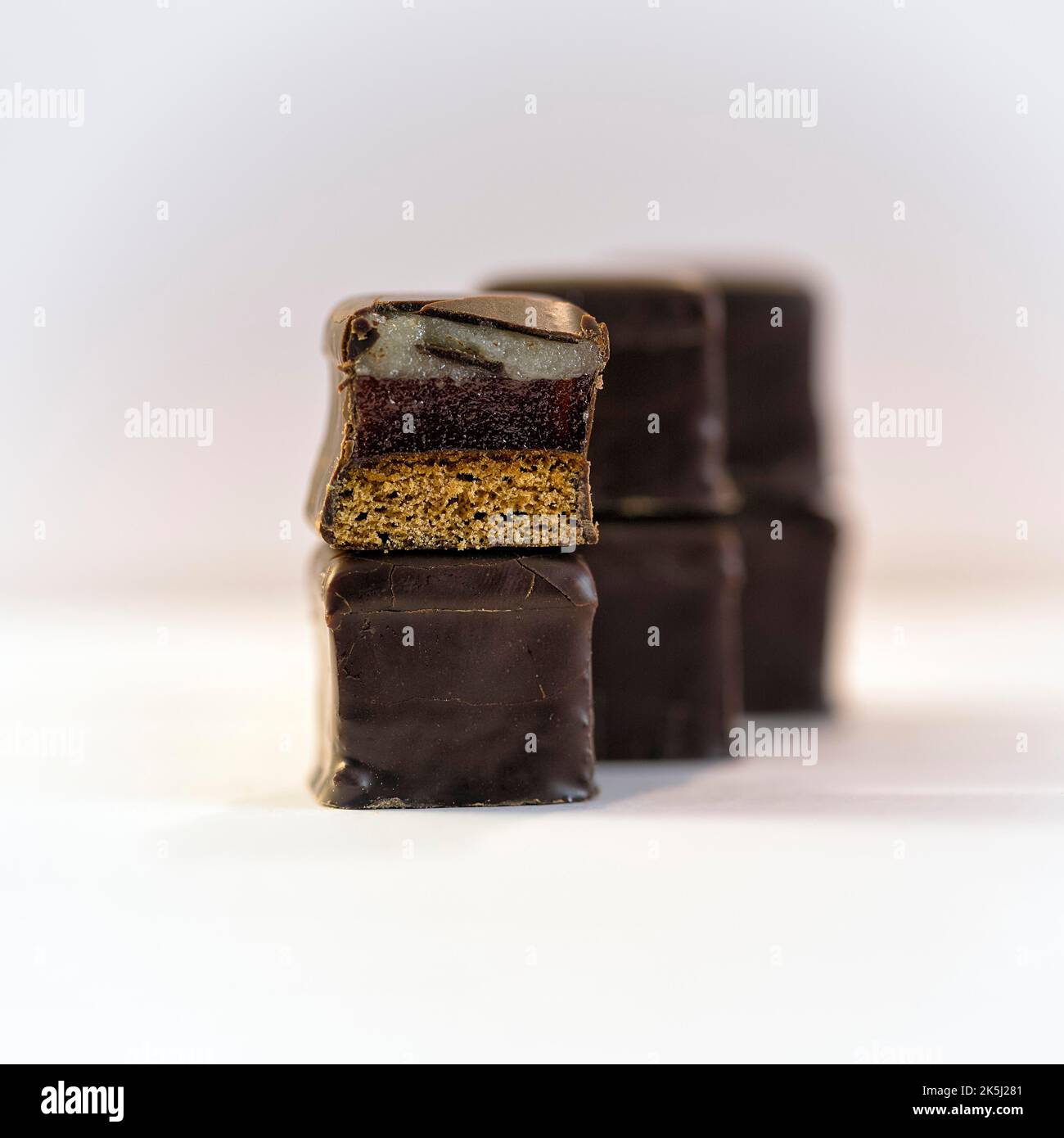 Dominos in a row, stacked, Christmas sweet with layers of marzipan, gingerbread and dark chocolate icing, half, close-up Stock Photo