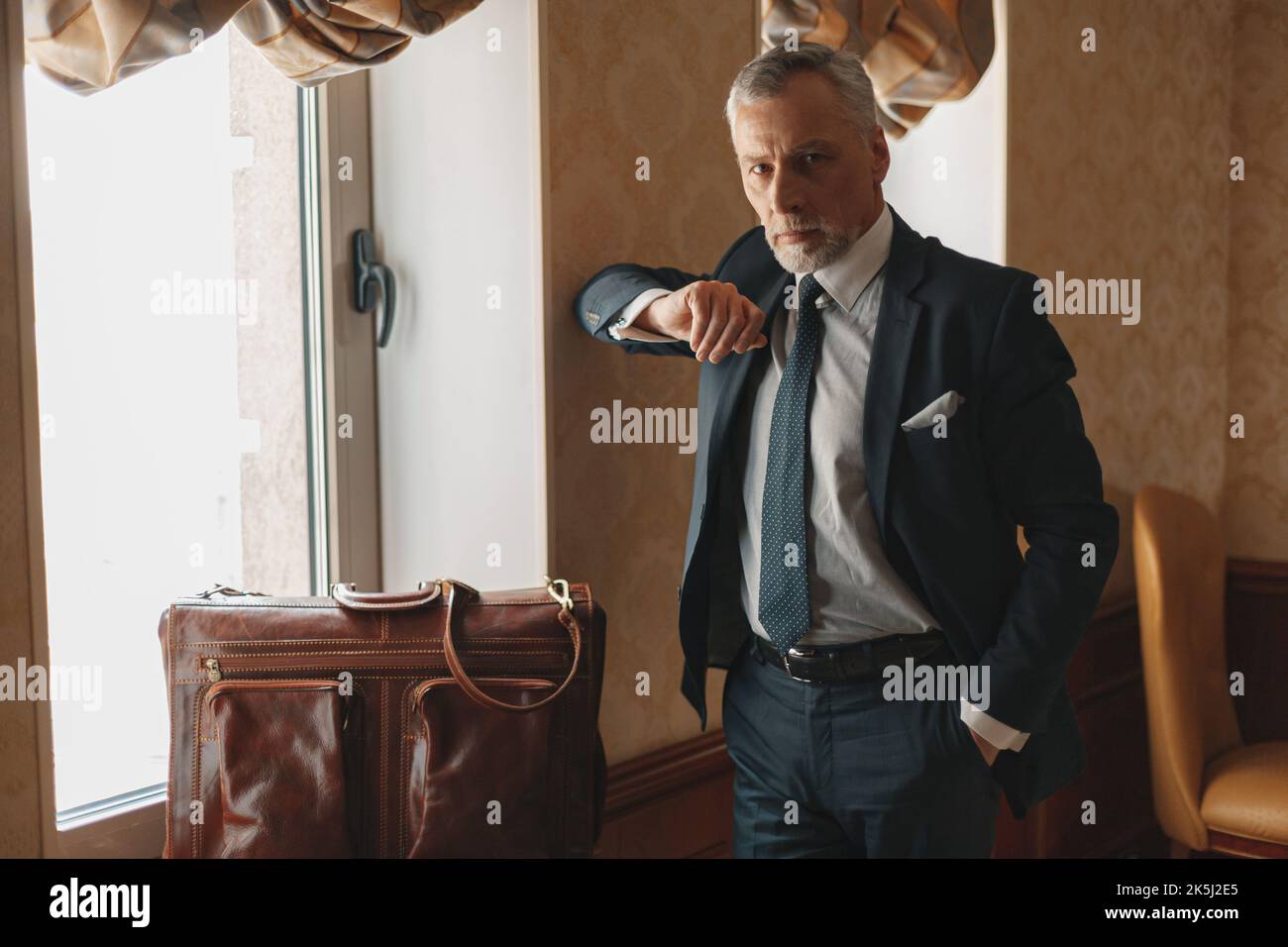 Focused businessman standing with luggage while waiting for checkin in