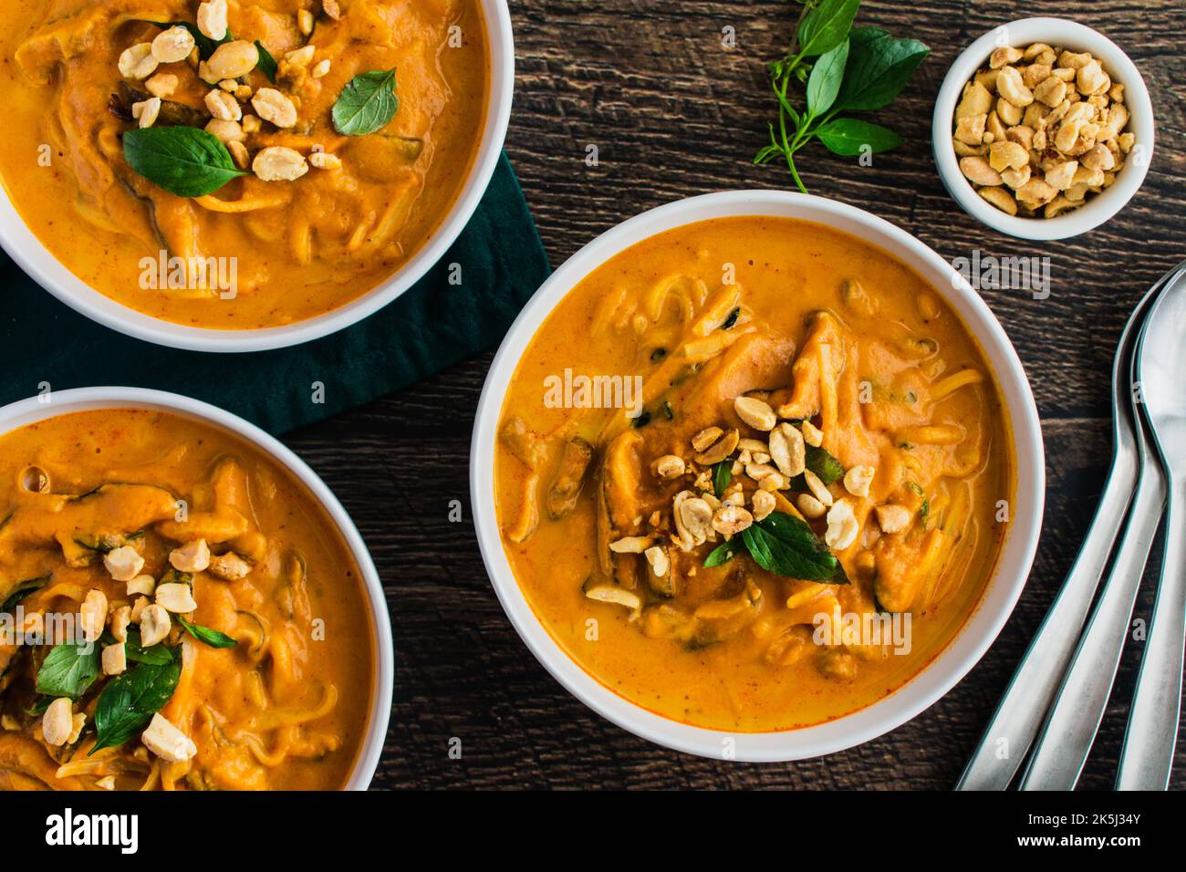 Spicy Thai Curry Pumpkin Noodle Soup Garnished with Peanuts and Thai