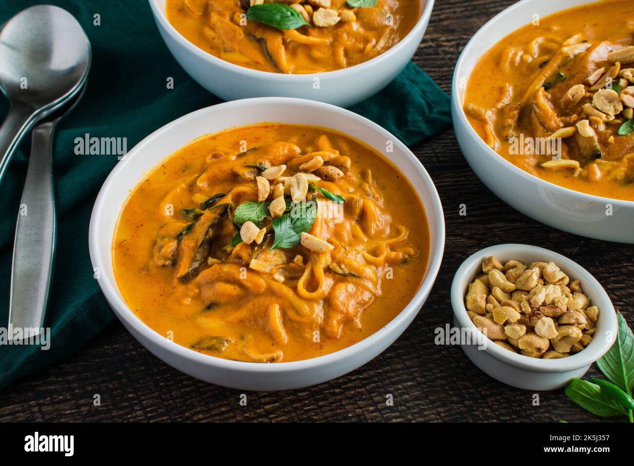 Spicy Thai Curry Pumpkin Noodle Soup Garnished with Peanuts and Thai