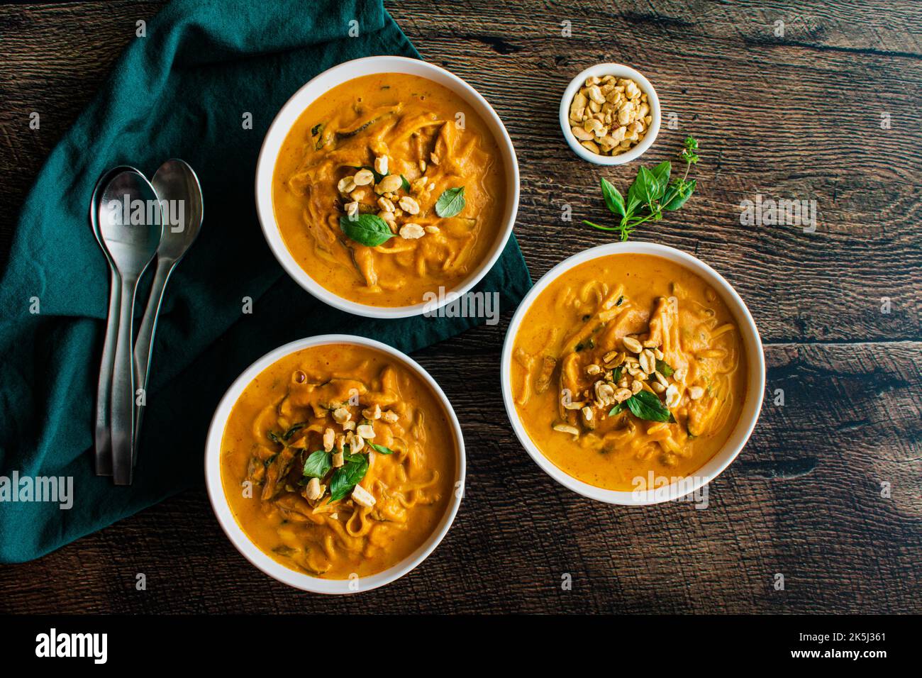 Spicy Thai Curry Pumpkin Noodle Soup Garnished with Peanuts and Thai