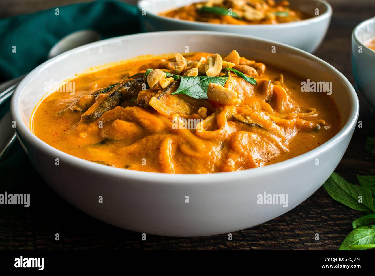 Spicy Thai Curry Pumpkin Noodle Soup Garnished with Peanuts and Thai