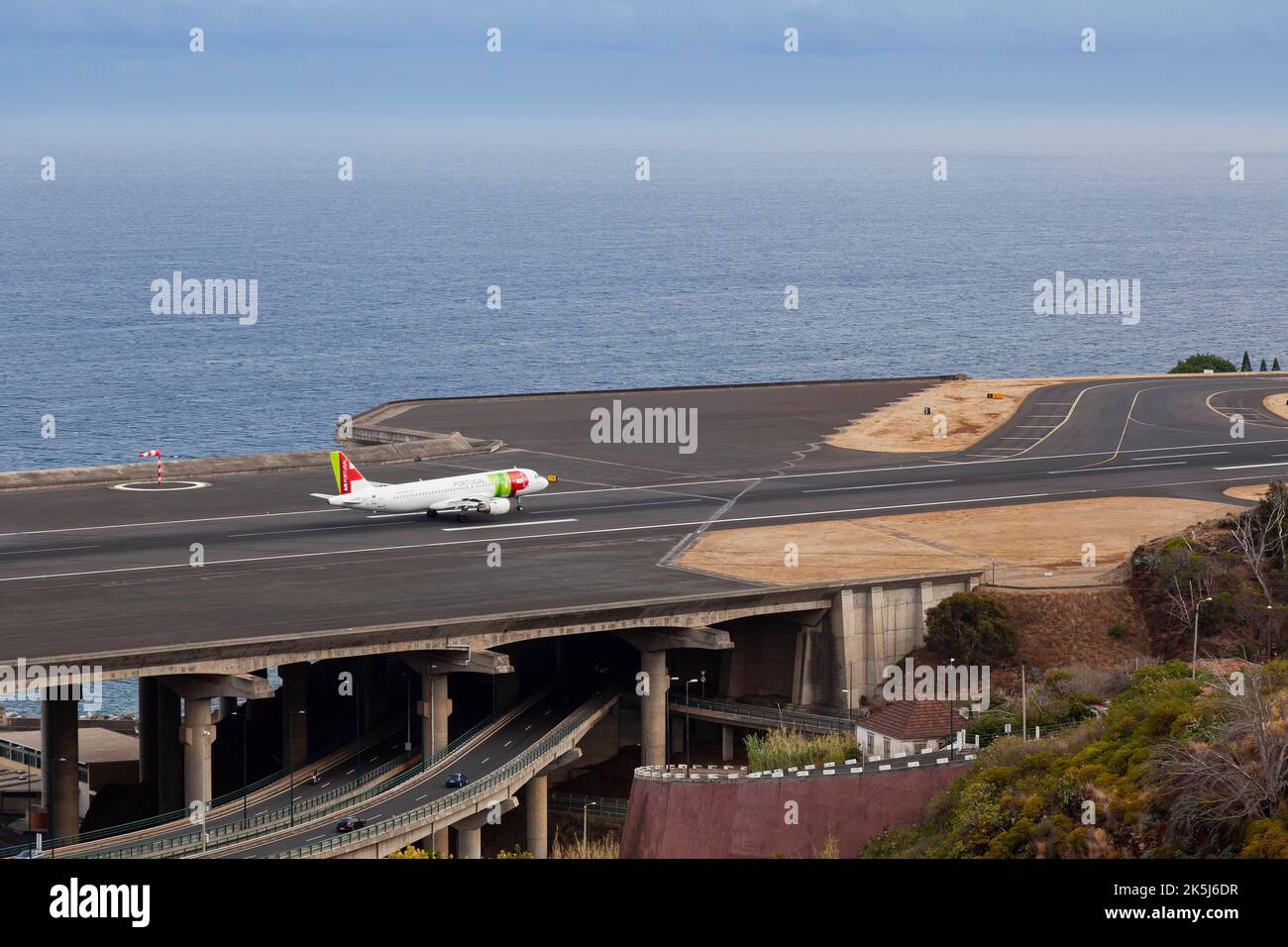 Airbus from TAP Portugal approaching the runway of Madeira Airport LPMA, also known as Funchal Airport and Santa Catarina Airport, next to a busy Stock Photo