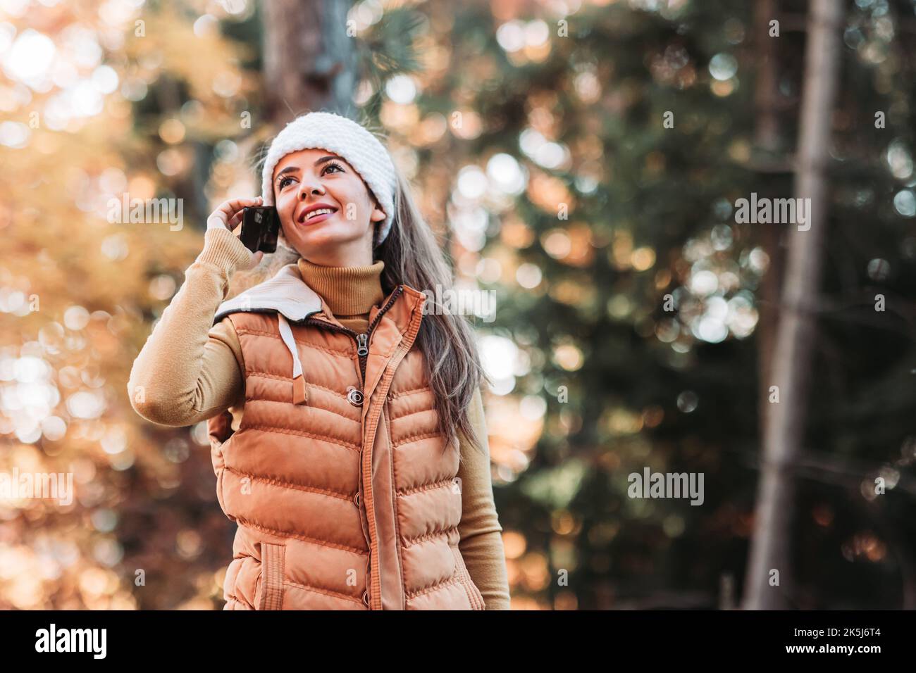 Young, female person talking over the phone in the woods Stock