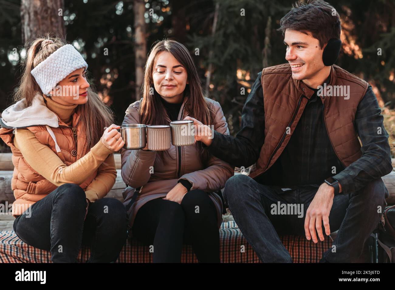 Three friends drinking tea from the metal, steel cups outdoors Stock Photo