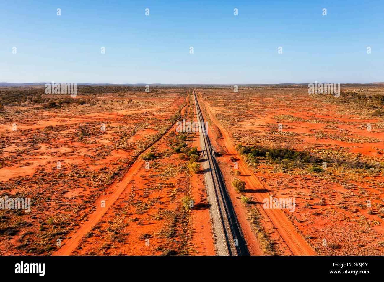 Remote red soil Australian outback with single line of railway to Broken Hill city - aerial mid-air landscape view. Stock Photo