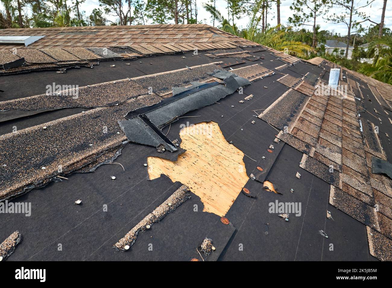 Damaged house roof with missing shingles after hurricane Ian in Florida