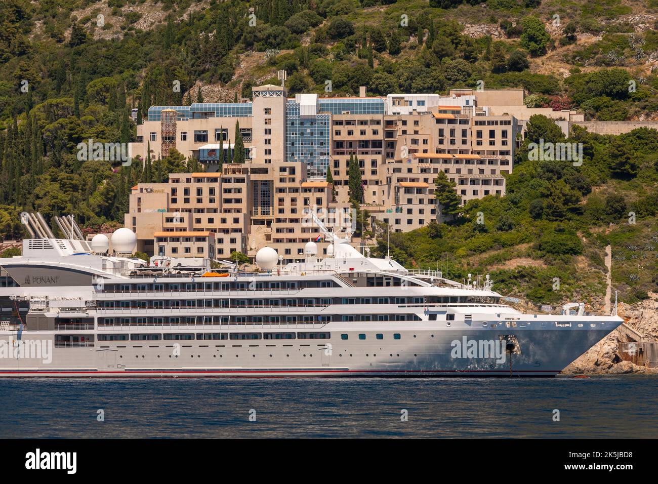 DUBROVNIK, CROATIA, EUROPE - Cruise ship Le Lyrial anchored in front of abandoned Hotel Belvedere, near Dubrovnik. Stock Photo