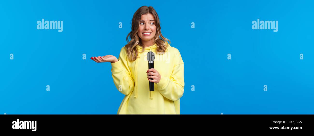 Awkward cute blond girl dont know lyrics as singing karaoke, looking at