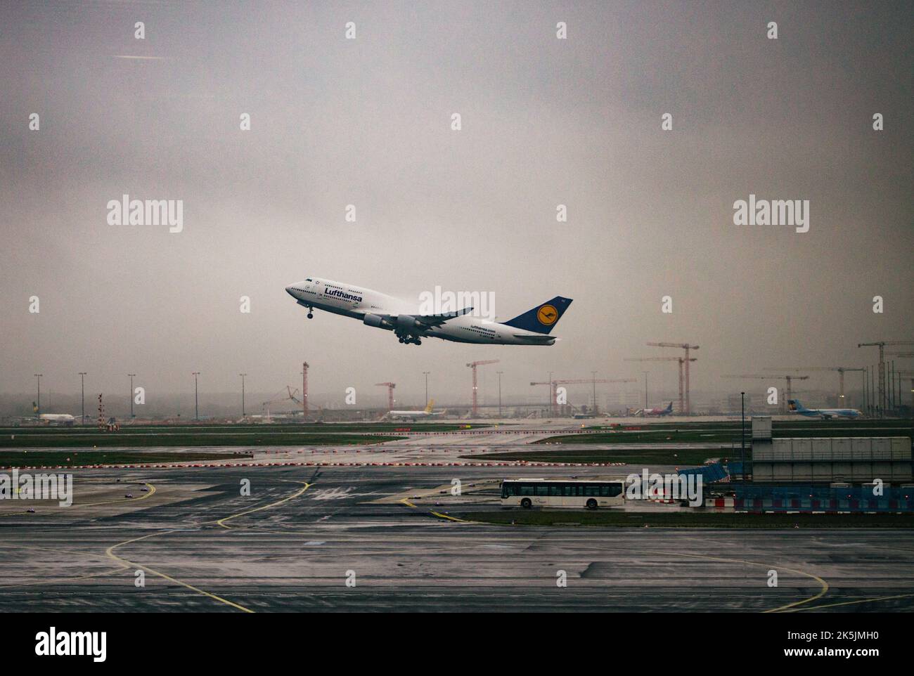 A Lufthansa plane taking off from the Frankfurt airport under a gloomy sky on a rainy day in Germany Stock Photo