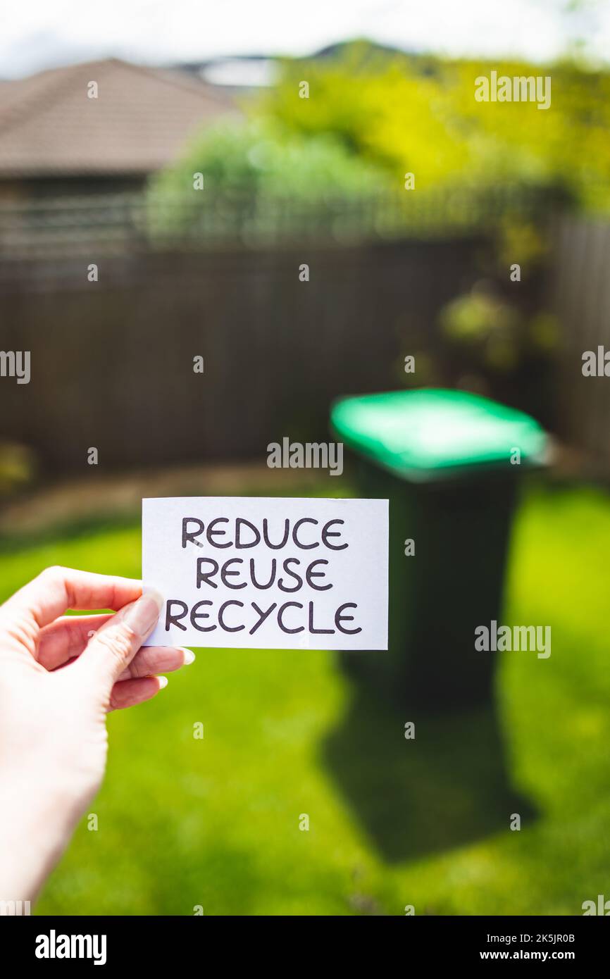 reduce reuse recycle sign in front of backyard bokeh with garbage bin ...