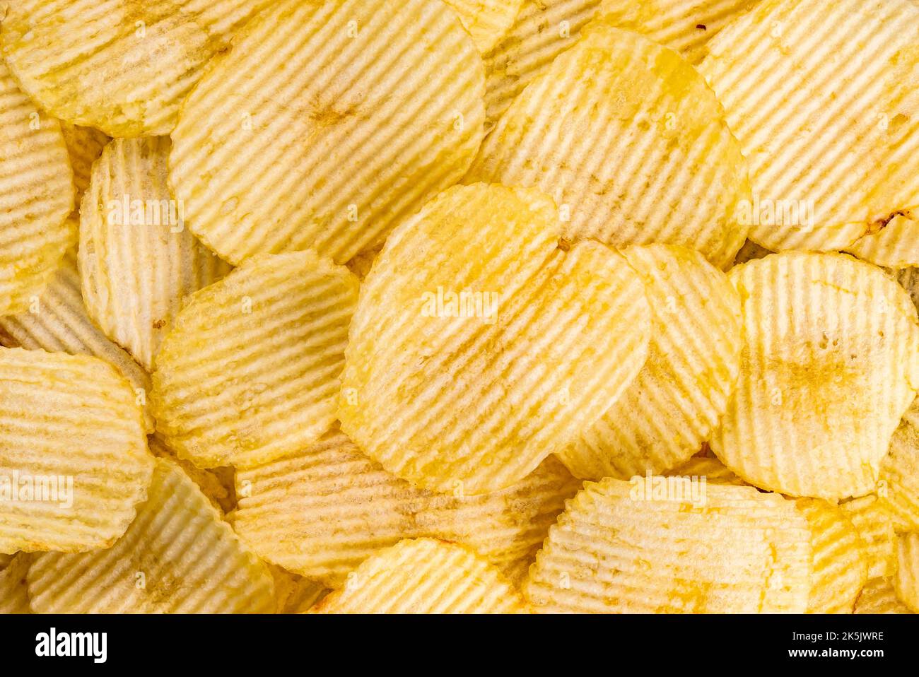 Top view of salted dry crispy fried corrugated potato chips. Crispy