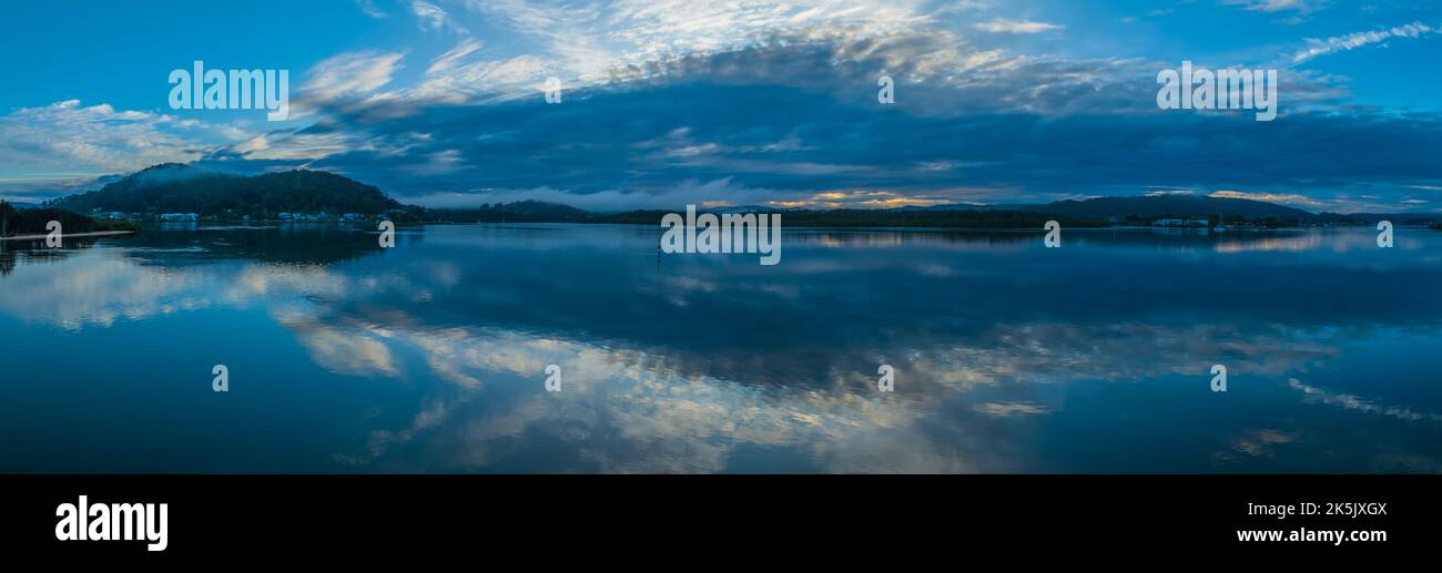 Aerial sunrise waterscape with rain clouds, mist and reflections in Woy Woy on the Central Coast, NSW, Australia. Stock Photo