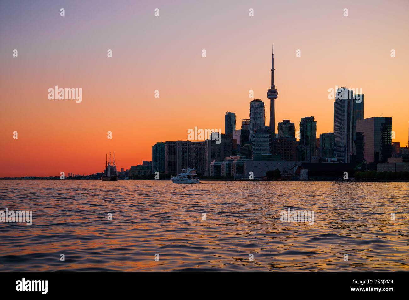 Toronto downtown cityscape with skyscrapers, white yacht, old sail ship and amazing color sunset sky. Travel and transportation Stock Photo