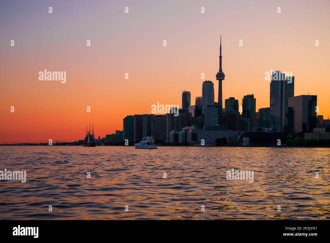 Toronto downtown cityscape with skyscrapers, white yacht, old sail ship and amazing color sunset sky. Travel and transportation Stock Photo
