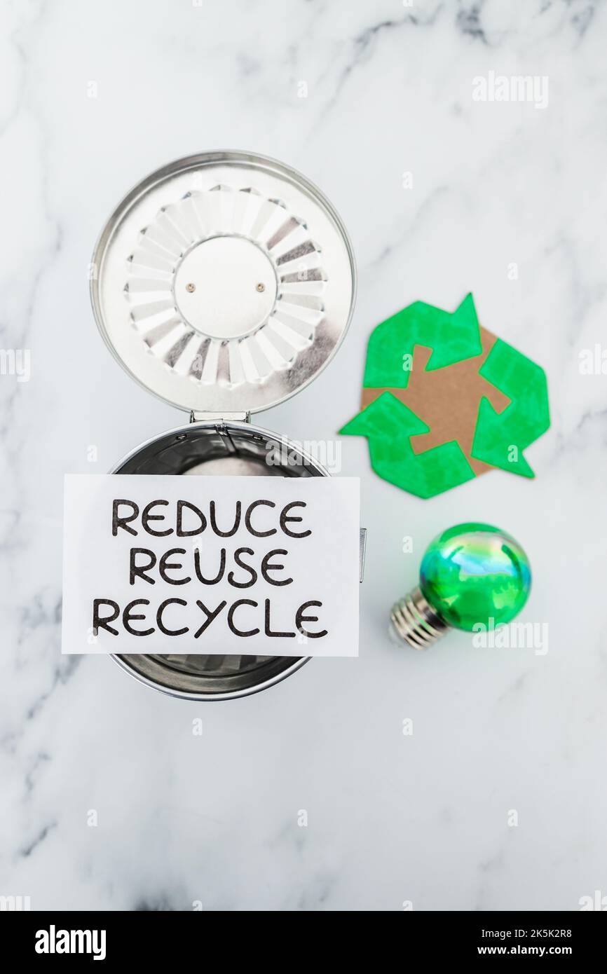 reduce reuse recycle sign with mini trash can next to green light bulb ...