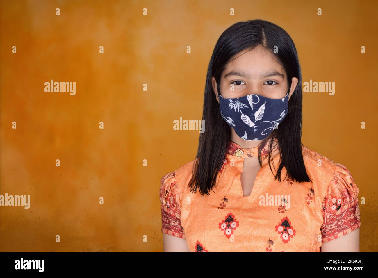 teenage girl with face mask against orange background Stock Photo